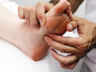 A foot being examined by a health professional