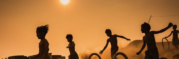Children play against a setting sun
